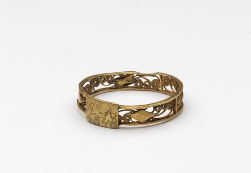 Gouden ring met cantillewerk en tussen twee banden filigrainwerk, vierkant schildje waarop AA…