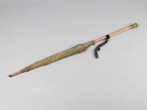 Een lichtgroene, changeantzijden parasol, zeer lange steel, waaronder blauw fluwelen band waaraan…