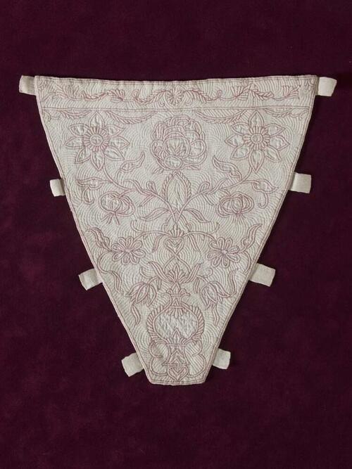 Borstlap of stomacher, driehoekig van vorm met bloemornament in roze zaans stikwerk