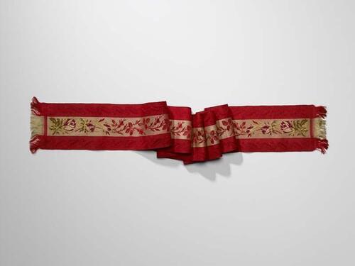 Smal rood zijden sjaaltje met franje, in het midden een lichte baan met ingeweven bladrank