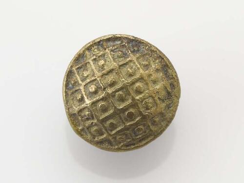 Ronde, bolle knoop met langs de randen een gallde contour en een vlak verdeeld in ruiten