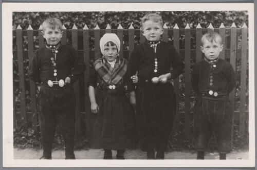 Drie jongens en een meisje in Urker streekdracht, circa 1925