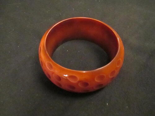 Armband, type 'bangle', van roze/bruin plastic met uitgediepte 'vlekken'