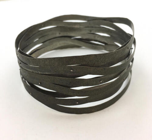 Armband van elf metalen armbanden die met klinknagels aan elkaar verbonden zijn