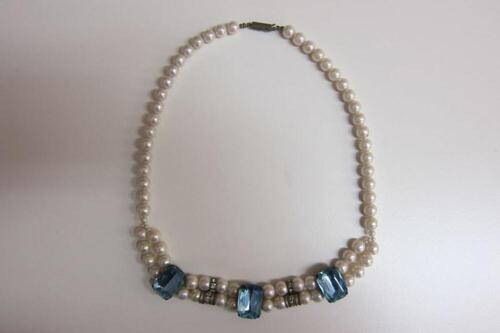 Halsketting in witte plastic parels met blauwe fantasiestenen
