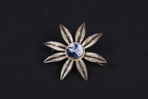 Bloemvormige broche in filigraan zilver met Hollands tafereel in Delfts