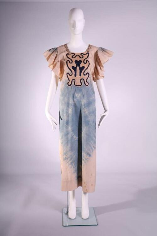 Jurk in beige met blauwe batik tekening. Ronde halsuitsnede en geplooide kapjes aan de armuitsnede…
