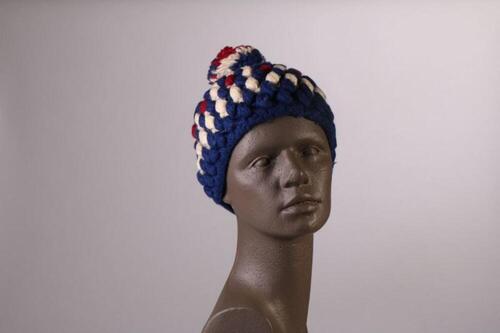 Muts in blauwe wol met rood en wit en grote pompon