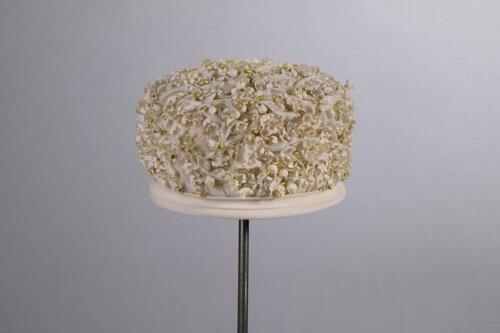 Hoed in witte gedrapeerde nylon met stoffen meiklokjes