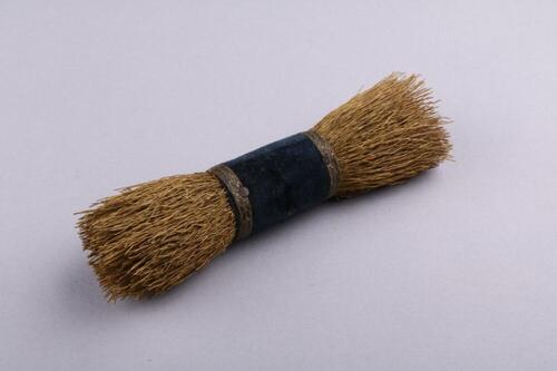 Hoedenborstel in stijf naturel stro, gebundeld met een lint in zwart fluweel