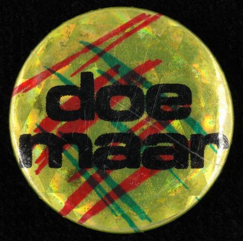 Kleine ronde "Doe Maar" button: geel met holografische effecten, groene en rode strepen, opdruk …