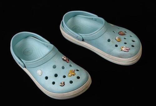 Paar lichtblauwe crocs, maat "7", in de ventilatiegaatjes gedecoreerd met Disneyfiguren en…