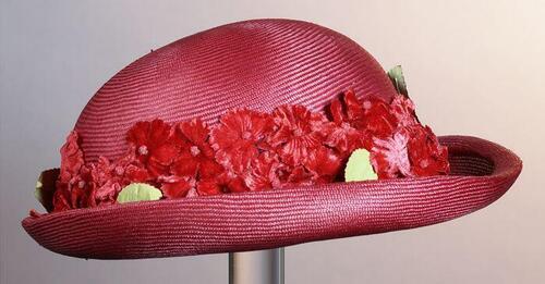 Rood strohoedje met rand van fluwelen rode bloemen en groene bladeren