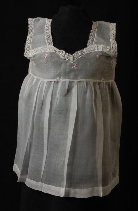 Babyjurk, mouwloos schortmodel van transparant wit nylonmet kleine machinaal geborduurde roze en…