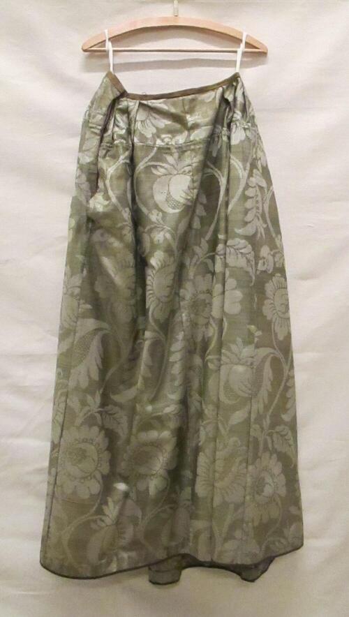 Rok van damast, mosgroen met beige gekalanderde wol (grein), met grote florale motieven. Voorpand…