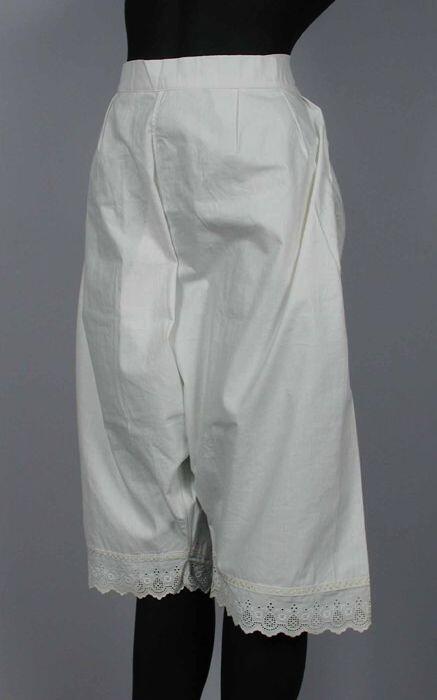 Witte katoenen onderbroek met pijpen versierd met bandje en broderie, sluit met striklinten opzij