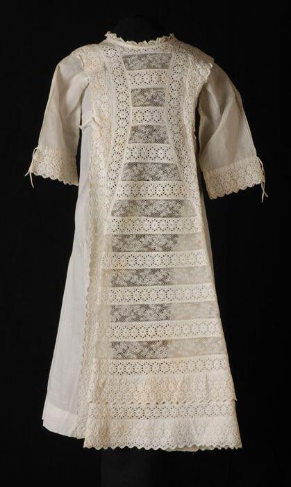 Doopjurk van wit mousseline, prinsesselijn met een zandlopervormig front van broderie en kant,…