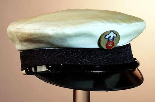 Ronde schipperspet met witte bol, zwarte band en klep, embleem met gekroonde "W"