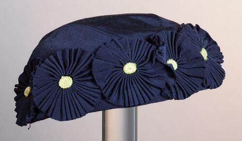 Kapje van donkerblauw ripszijde garnering van bloem-rozetten van hetzelfde materiaal met gele harten