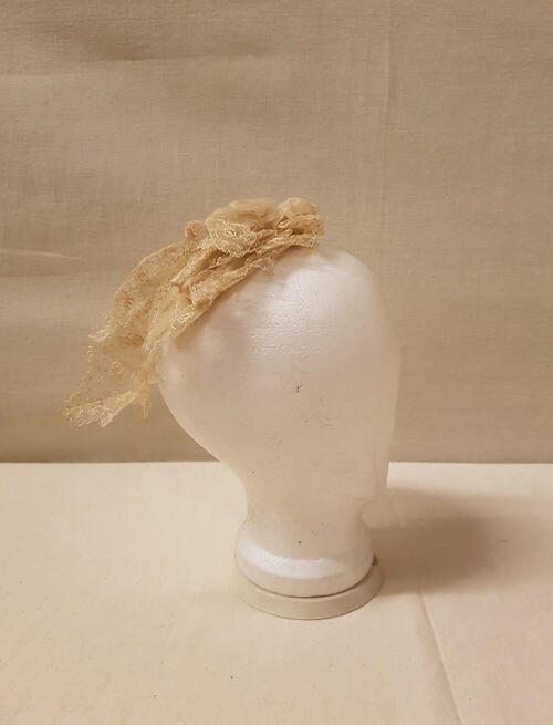 Coiffure / Kap bestaande uit stroken crèmekleurige effen organdie, machinaal geborduurd met…