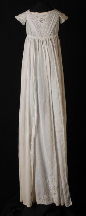 Lange witte doopjurk, zandlopermodel, korte mouw, versieringen met broderie