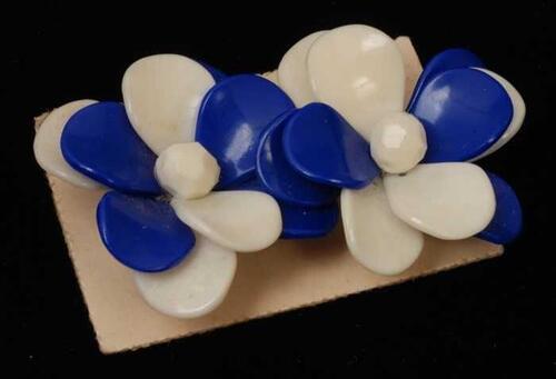 Paar oorbellen, clip met bloem van blauw en wit plastic, op wit karton, kapper Van Vliet