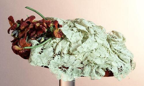 Dameshoed van rood velours en crèmekleurig kant, garnering van bloemen van textiel in rood-tinen