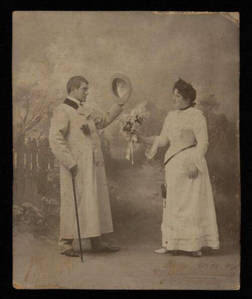Foto van actrice Marie van Eysden-Vink; heer met hoed begroet dame met bloemen