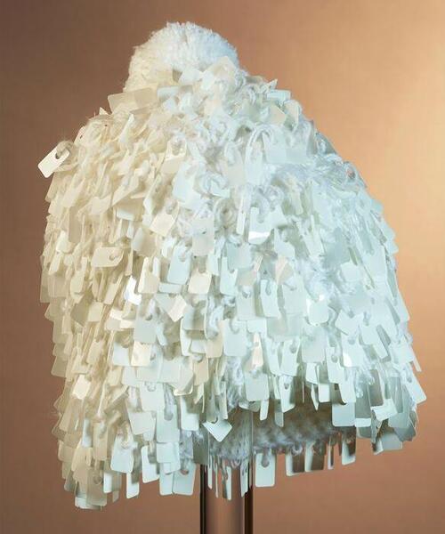 Witte gehaakte muts met ingebreide witte plastic rechthoekige pailletten en een pompon bovenop