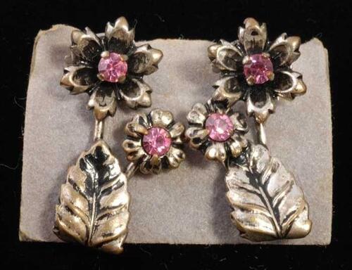 Eén paar oorbellen, clip met zilverkleurig bloemetjes en blaadje en roze kunstdiamantjes, op grijs…
