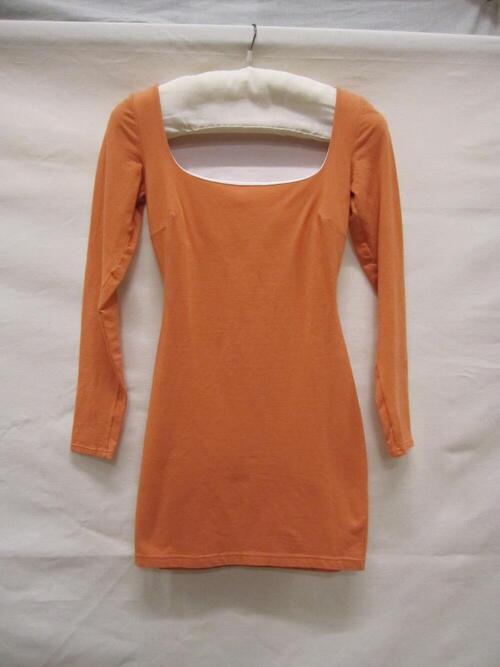 Mini-jurk van oranje tricot. Model met lange mouwen en laag decolleté. Overslagje van witte stof
