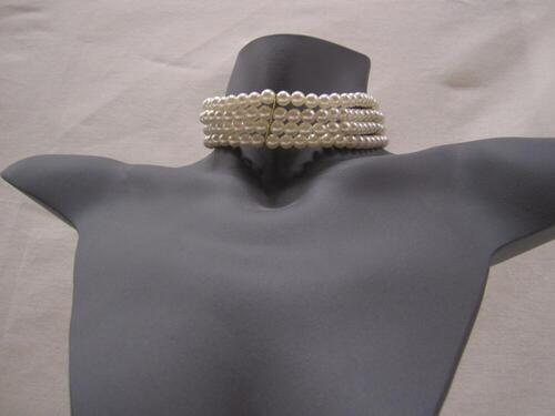 Ketting bestaande uit 4 rijen witte parels, welke onderbroken worden door 3 goudkleurige plaatjes