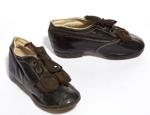 Een paar schoenen van zwart leer (kind), met bruin zijden strik en veter
