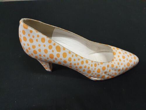 Een paar schoenen, model pump van leer bekleed met witte stof bedrukt met oranje stippen, smal…