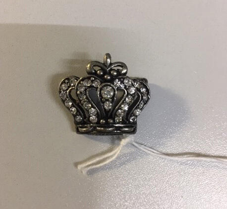 Broche. In vorm van kroontje, zilverkleurig/zwart metaal bezet met witte strass-stenen.