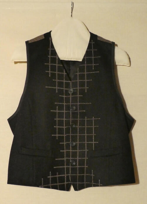 Vest (man) van zwarte stof. Op voorpand bruin asymmetrisch machinaal borduursel in ruitmotieven,…