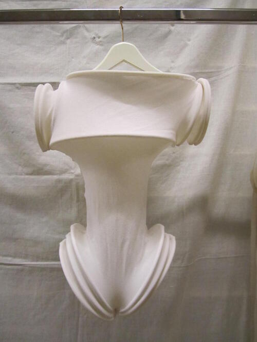 Mini-jumpsuit (vrouw), koker van wit tricot, met diverse ingestikte, flexibele, kunststof ringen