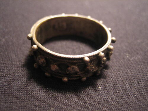 Zilveren 'Akkelde ring'. Rand met stipjes, middenband met rozetjes en knopjes