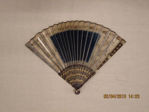 Vouwwaaier, montuur van hout met goudkleurige ornamenten, blad van in goud beschilderd gaas met…
