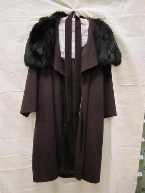 Mantel van donkerbruin laken/wol, driekwart model met strikceintuur en kraag van zwart konijnenbont…