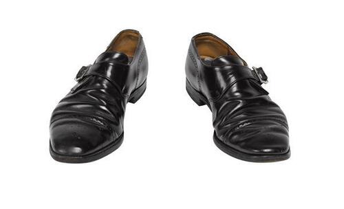 Een paar mannenschoenen, model van zwart leer met gesp, en patroon van kleine gaatjes bij neus