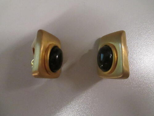 Oorclips, rechthoekig model van matglanzend goudkleurig metaal, waarop bruine glascabochon met…