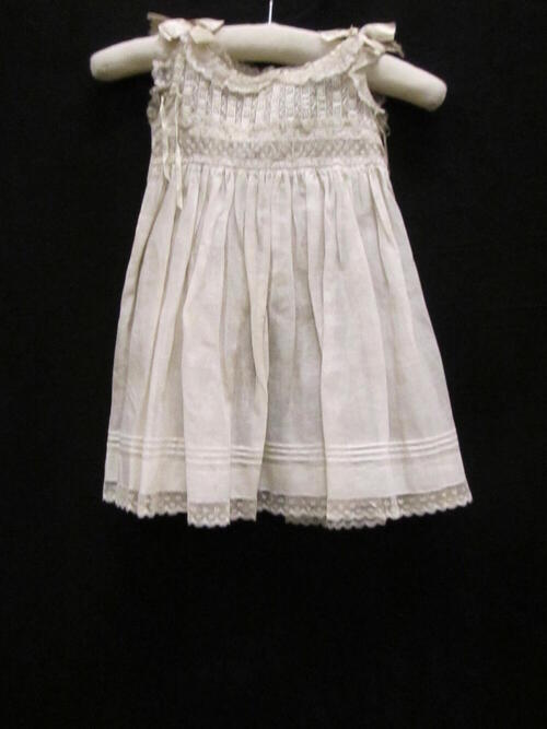 Schort (vrouw/kind) van wit katoenbatist met garnering van machinaal kant en machinale broderie