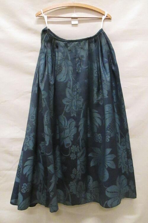 Rok van donkerblauw en blauw wollen damast met grote florale motieven. Voorpand vlak aan de rokband…