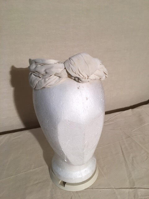 Haarband van witte crepe stof. Knoop middenvoor
