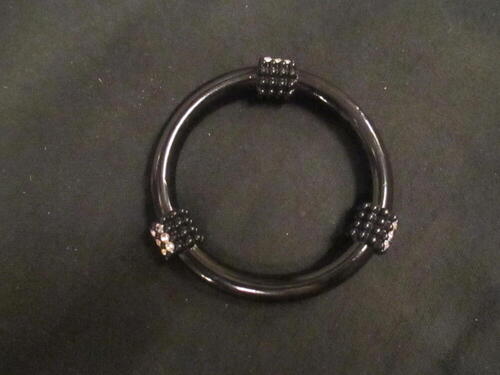 Armband, type bangle, van zwarte kunststof, drie opstaande gedeeltes met bobbelreliëf bezet met…