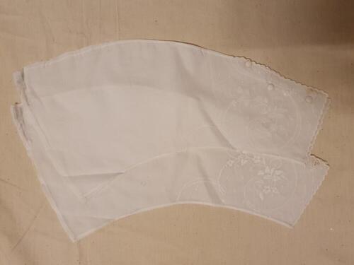 Jasje (baby) van beige zijde, langs de hals afgebiesd met rood zijden lint, voering van grof wit…