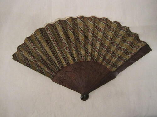 Vouwwaaier, montuur van bewerkt bruin hout, blad van veelkleurig pluche met patroon van diagonale…