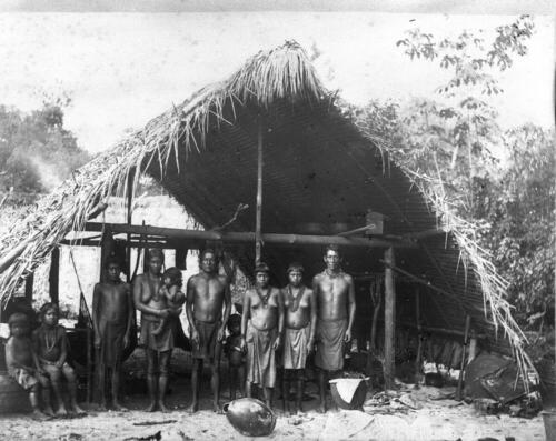 Een groep inheemsen staat voor een woning in een dorp bij de Jodensavanne - Boven Suriname