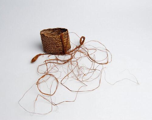 Armband (manchet) van gevlochten rotan met afhangende sagobladvezels